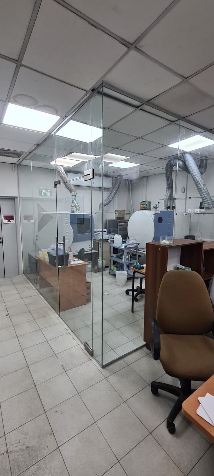 מחיצת זכוכית שקופה המחלקת חלל משרד עם דלת זכוכית וידיות נירוסטה